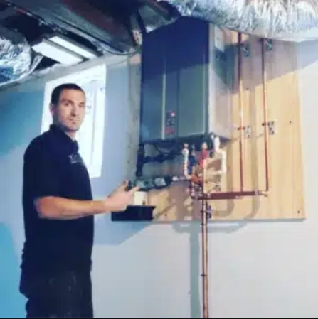 Plumber working on a tankless water heater installation in a basement.