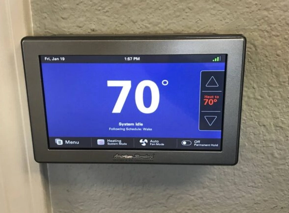 Smart thermostat display showing 70°F and system status.