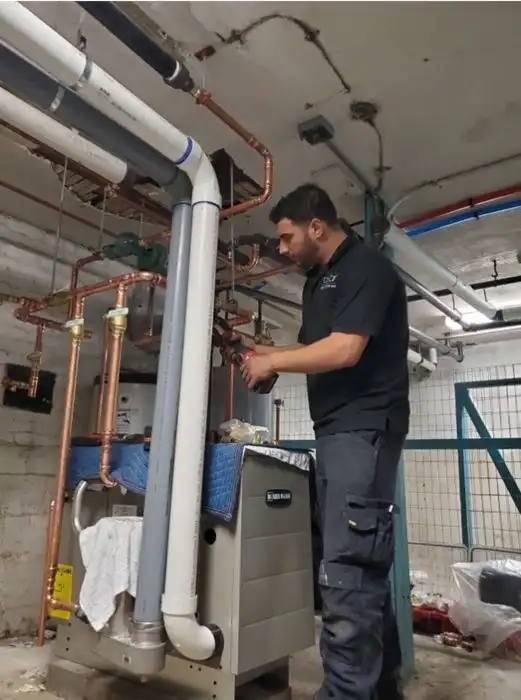 Screenshot_6 Plumber working on a heating system with copper pipes in a basement.