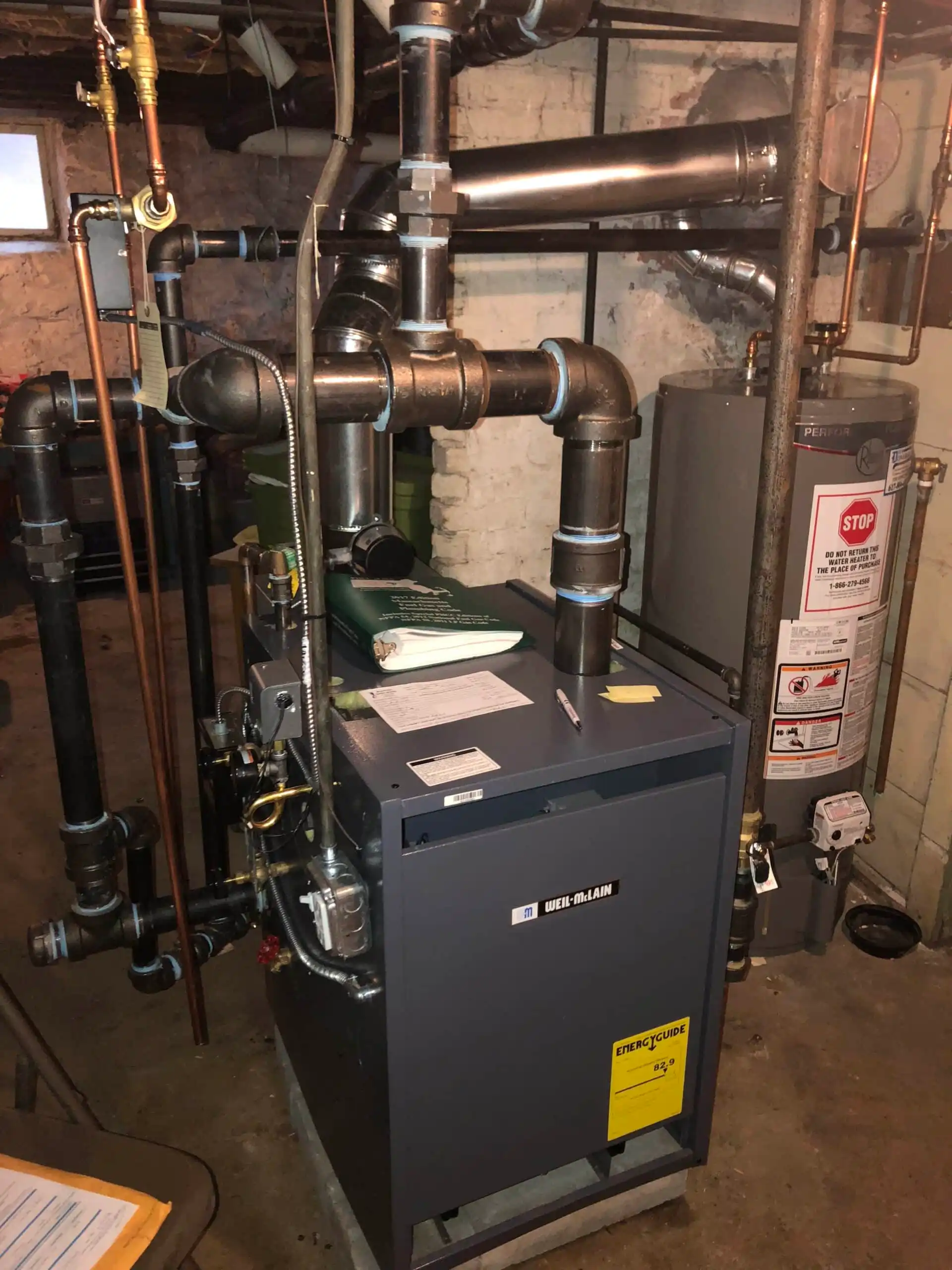 Steam-Boiler-scaled Residential boiler system with pipes and water heater in a basement.