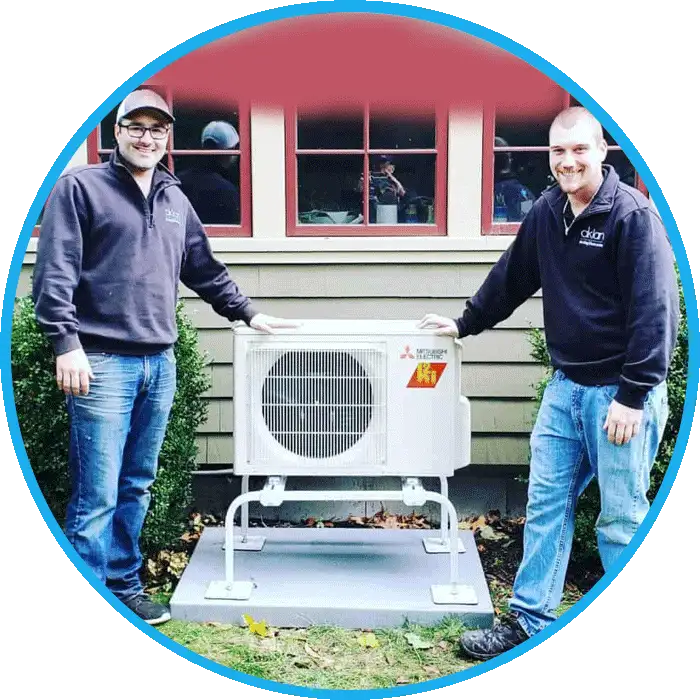 imgpsh_fullsize_anim-7 Two technicians standing next to a newly installed air conditioning unit outside a house.