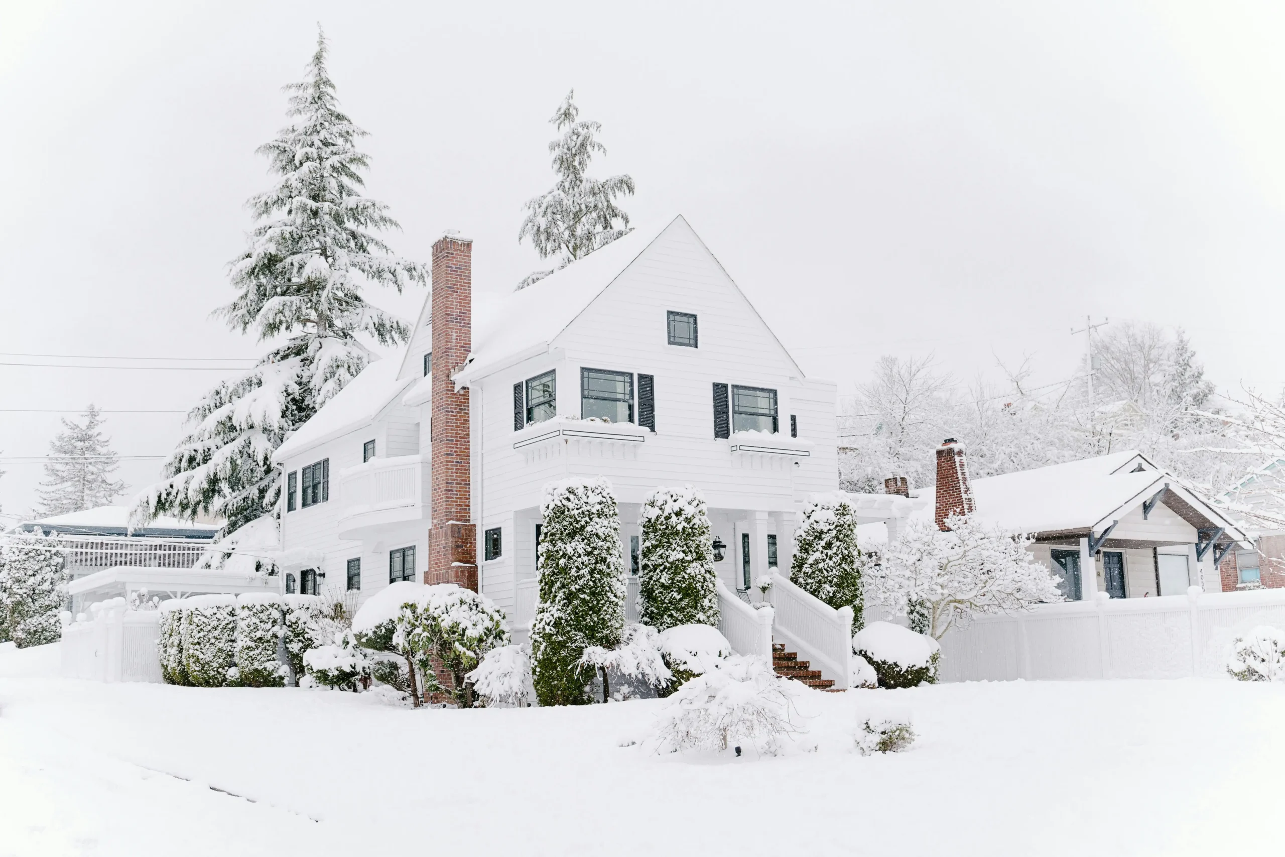 winter White house covered in snow with evergreen trees in winter landscape.
